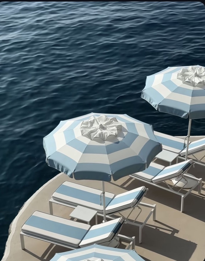 Blue-striped parasols beside deep-blue water.
