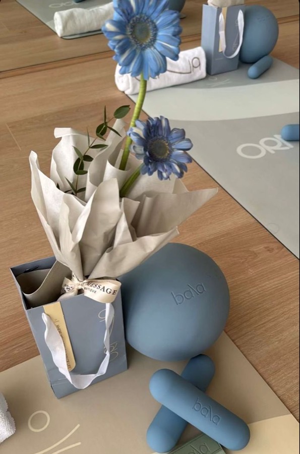 Blue Pilates props and flowers arranged on studio mats.