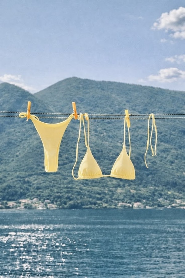 A yellow swimsuit drying above a sunlit lake.